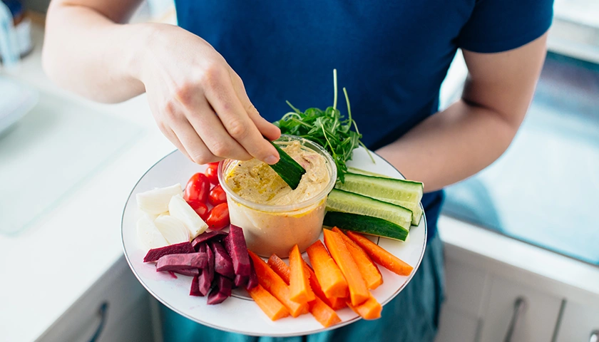 Hombre comiendo hummus para beneficiarse de las propiedades de las legumbres.webp